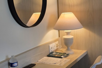 Salle de restaurant lumineuse avec tables dressées, chaises en bois sombre, étagères décoratives et plantes vertes.
