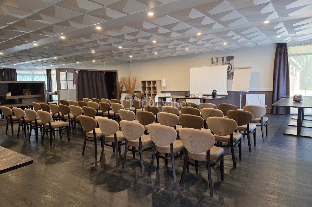Salle de conférence lumineuse avec chaises alignées, écran de projection, tableau blanc et décor moderne.