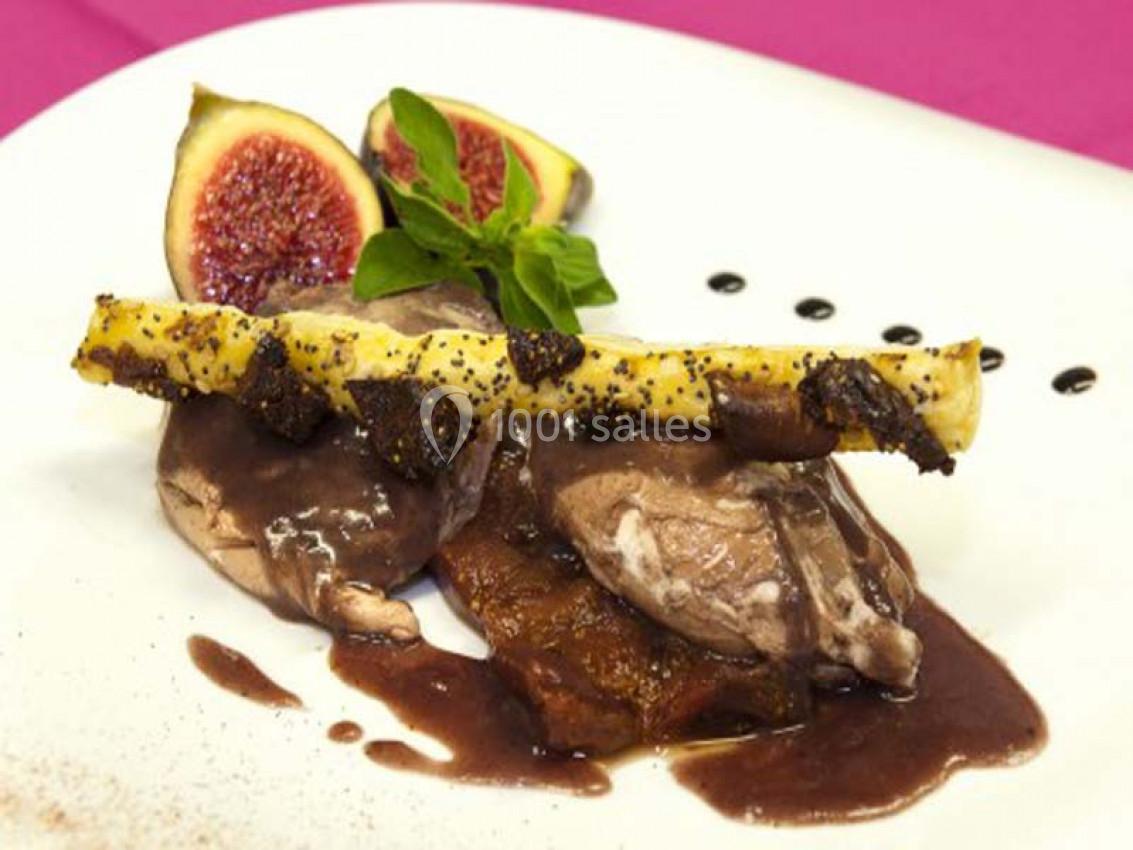 Plat gastronomique composé de viande nappée de sauce, accompagné de figues fraîches, d'une garniture et d'un décor soigné.