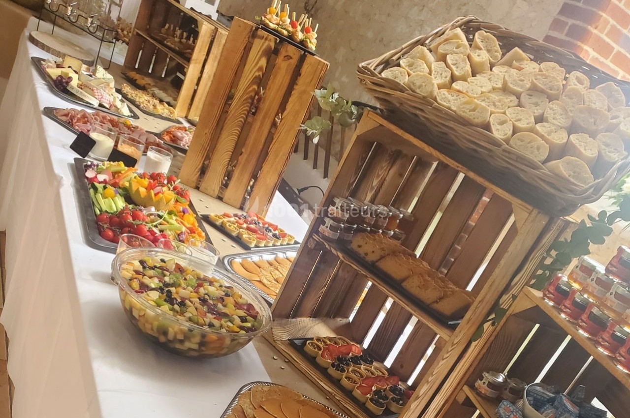 Buffet varié avec pains, fruits, légumes, verrines et autres plats disposés sur des caisses en bois.