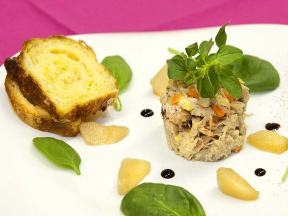 Assiette composée d'une terrine de poisson garnie de feuilles de mâche, poires pochées et pain brioché.