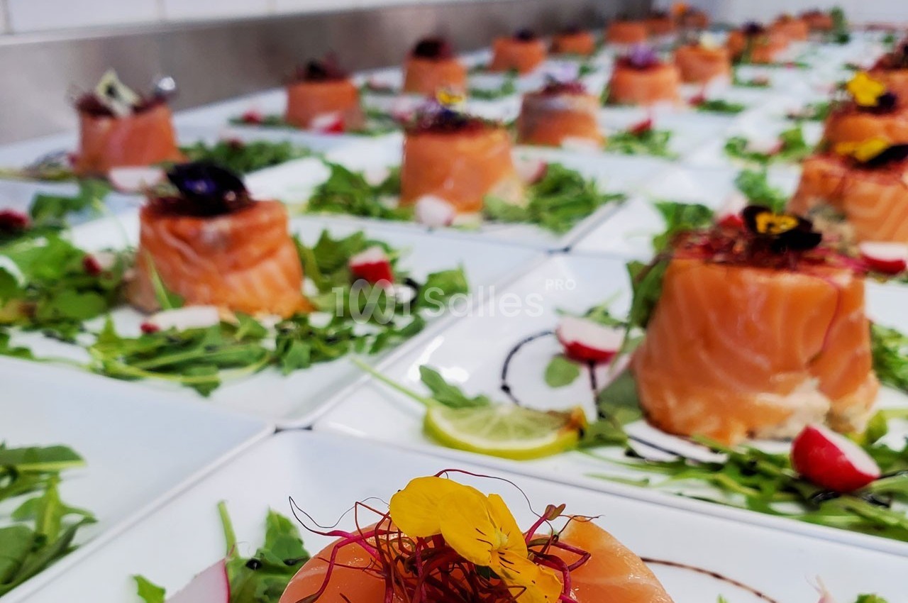 Assiettes de saumon fumé dressées sur un lit de roquette avec des garnitures colorées et des fleurs comestibles.