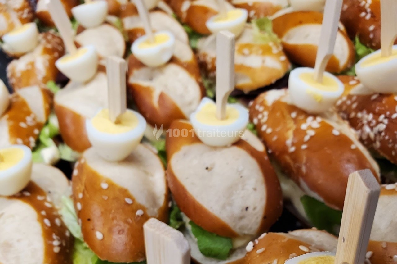 Mini-sandwiches au pain bretzel garnis de salade et surmontés de demi-œufs durs fixés avec des piques en bois.