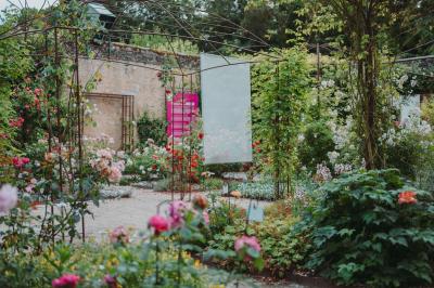 Écran lumineux affichant des images colorées dans un jardin fleuri à la tombée de la nuit.