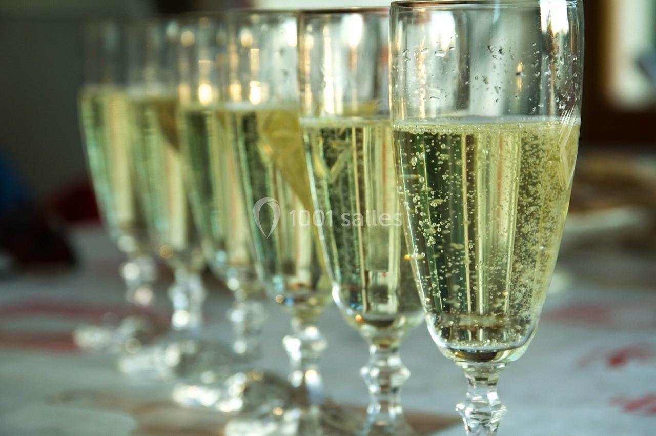 Six flûtes remplies de champagne alignées sur une table blanche.