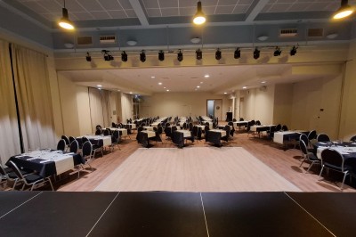 Salle de conférence lumineuse avec tables disposées en U, écran de projection et grandes fenêtres donnant sur l'extérieur.