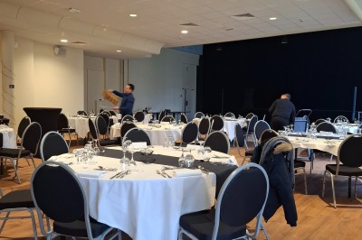 Salle de conférence lumineuse avec tables disposées en U, écran de projection et grandes fenêtres donnant sur l'extérieur.