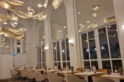 Salle de conférence lumineuse avec tables disposées en U, écran de projection et grandes fenêtres donnant sur l'extérieur.