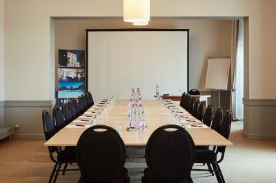 Façade d'un hôtel ancien à plusieurs étages, avec des fenêtres symétriques et un ciel bleu dégagé en arrière-plan.