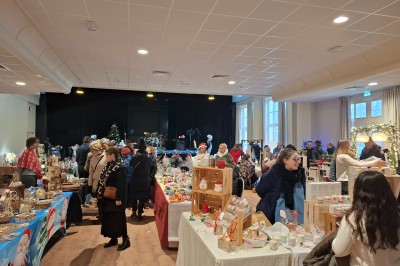 Tasse de café sur une table avec un macaron vert et un plateau de desserts flous en arrière-plan.