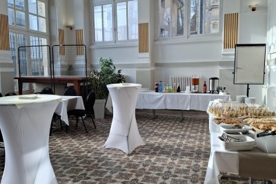 Tasse de café sur une table avec un macaron vert et un plateau de desserts flous en arrière-plan.