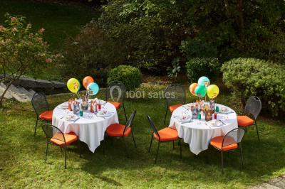 Un couple en tenue de mariage se tient devant une porte illuminée, entouré de briques et de végétation.