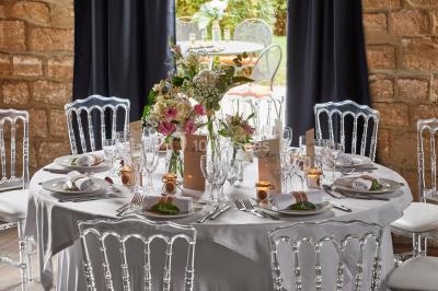 Un couple en tenue de mariage se tient devant une porte illuminée, entouré de briques et de végétation.