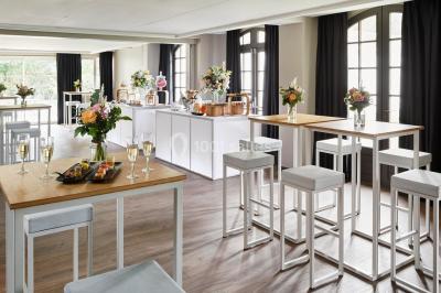 Un couple en tenue de mariage se tient devant une porte illuminée, entouré de briques et de végétation.