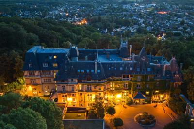 Un couple en tenue de mariage se tient devant une porte illuminée, entouré de briques et de végétation.