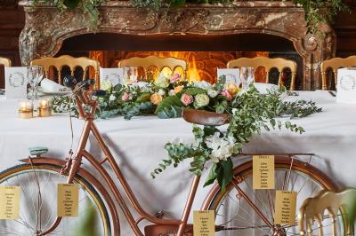 Un couple en tenue de mariage se tient devant une porte illuminée, entouré de briques et de végétation.