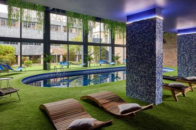 Un couple en tenue de mariage se tient devant une porte illuminée, entouré de briques et de végétation.