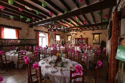 Espace extérieur avec balançoire, table et chaises blanches, parterre de fleurs rouges et jouet en plastique jaune.