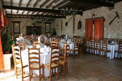 Espace extérieur avec balançoire, table et chaises blanches, parterre de fleurs rouges et jouet en plastique jaune.