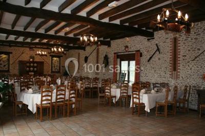 Espace extérieur avec balançoire, table et chaises blanches, parterre de fleurs rouges et jouet en plastique jaune.