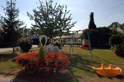 Espace extérieur avec balançoire, table et chaises blanches, parterre de fleurs rouges et jouet en plastique jaune.