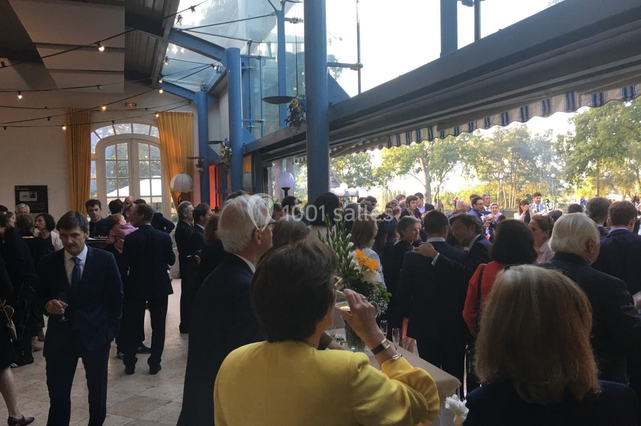 Groupe de personnes en tenue formelle lors d'un événement dans un espace lumineux avec de grandes baies vitrées.