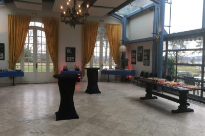 Table de ping-pong dans une pièce lumineuse avec canapé, fauteuil, décorations murales et fenêtres donnant sur la verdure.