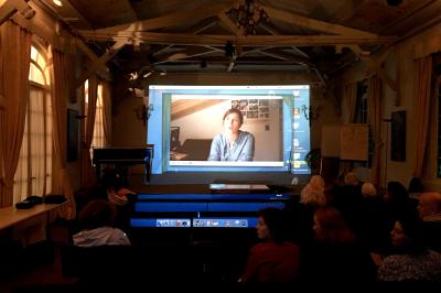 Table de ping-pong dans une pièce lumineuse avec canapé, fauteuil, décorations murales et fenêtres donnant sur la verdure.