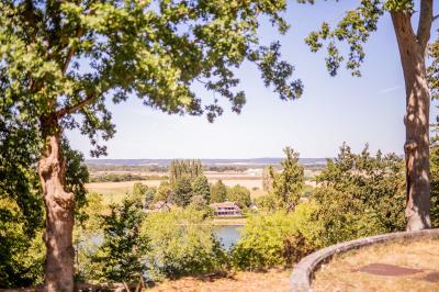 Table de ping-pong dans une pièce lumineuse avec canapé, fauteuil, décorations murales et fenêtres donnant sur la verdure.