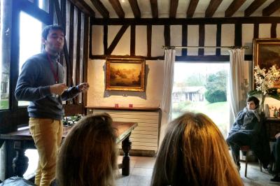 Table de ping-pong dans une pièce lumineuse avec canapé, fauteuil, décorations murales et fenêtres donnant sur la verdure.