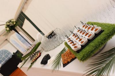 Buffet de petit-déjeuner avec viennoiseries, confitures, pains et boissons, près d'une baie vitrée donnant sur un jardin.