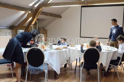 Buffet de petit-déjeuner avec viennoiseries, confitures, pains et boissons, près d'une baie vitrée donnant sur un jardin.