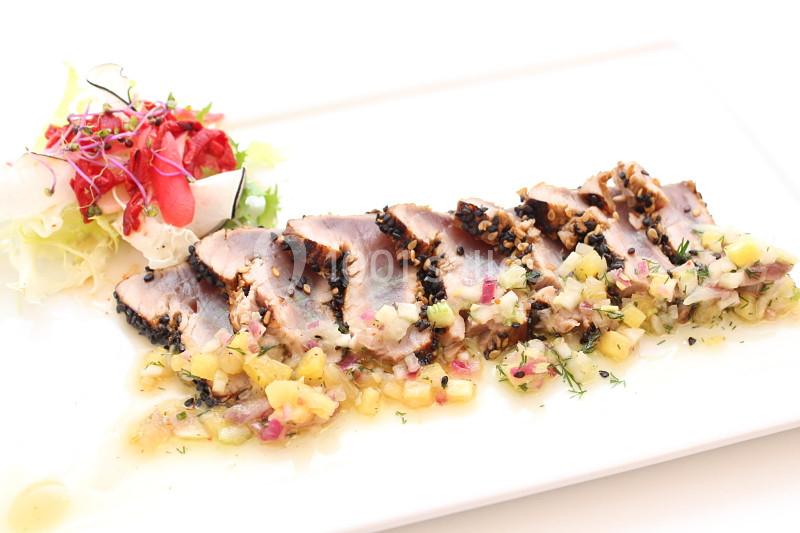 Tranches de thon mi-cuit en croûte d'épices, accompagnées d'une salsa de fruits et d'une salade colorée.