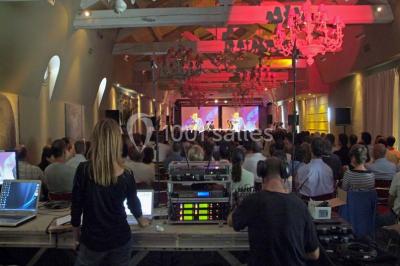 Terrain de tennis en plein air entouré de végétation et d'arbres, avec une clôture grillagée.