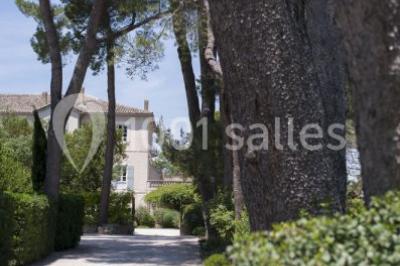 Terrain de tennis en plein air entouré de végétation et d'arbres, avec une clôture grillagée.