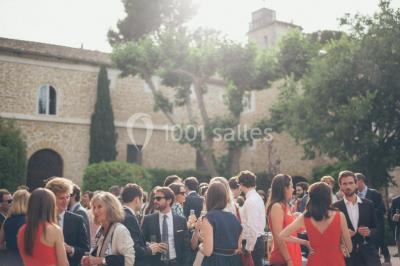 Terrain de tennis en plein air entouré de végétation et d'arbres, avec une clôture grillagée.