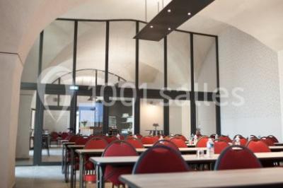 Terrain de tennis en plein air entouré de végétation et d'arbres, avec une clôture grillagée.