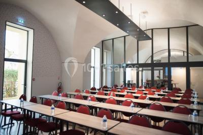 Terrain de tennis en plein air entouré de végétation et d'arbres, avec une clôture grillagée.