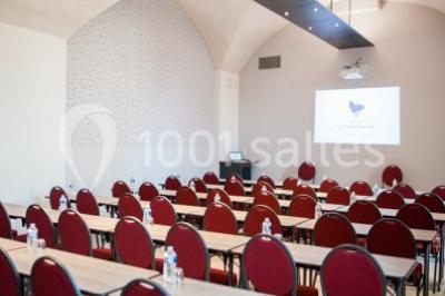 Terrain de tennis en plein air entouré de végétation et d'arbres, avec une clôture grillagée.
