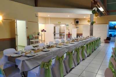 Salle de réception vide avec tables dressées pour un buffet, décor sobre et éclairage intérieur.