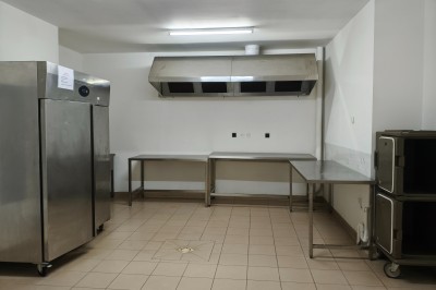 Salle de réception vide avec tables dressées pour un buffet, décor sobre et éclairage intérieur.