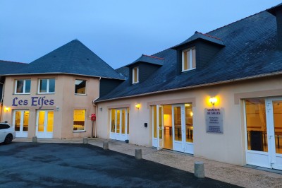 Salle de réception vide avec tables dressées pour un buffet, décor sobre et éclairage intérieur.