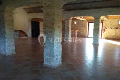 Chemin de gravier bordé de murets en pierre, menant à un paysage rural avec champs et arbres.