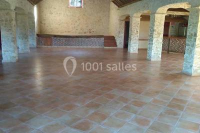 Chemin de gravier bordé de murets en pierre, menant à un paysage rural avec champs et arbres.