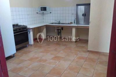 Chemin de gravier bordé de murets en pierre, menant à un paysage rural avec champs et arbres.