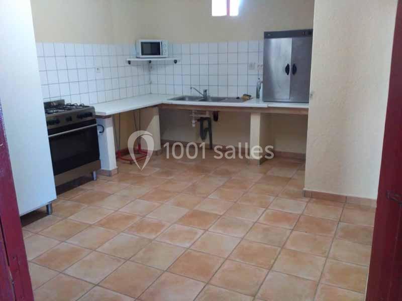 Cuisine simple avec carrelage au sol, évier, cuisinière, micro-ondes et grand placard métallique.