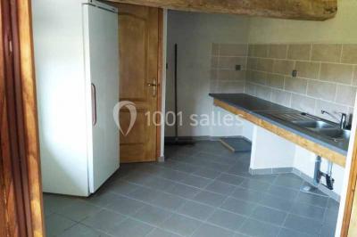 Chemin de gravier bordé de murets en pierre, menant à un paysage rural avec champs et arbres.