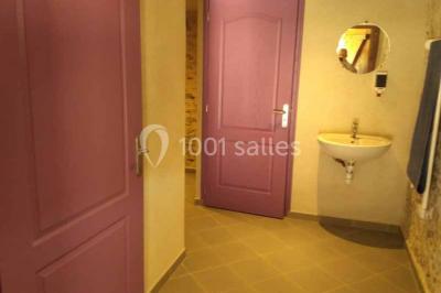 Chemin de gravier bordé de murets en pierre, menant à un paysage rural avec champs et arbres.