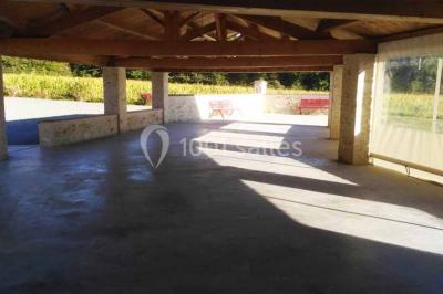 Chemin de gravier bordé de murets en pierre, menant à un paysage rural avec champs et arbres.