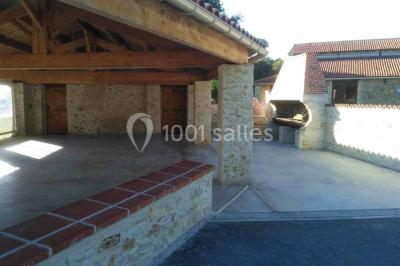 Chemin de gravier bordé de murets en pierre, menant à un paysage rural avec champs et arbres.